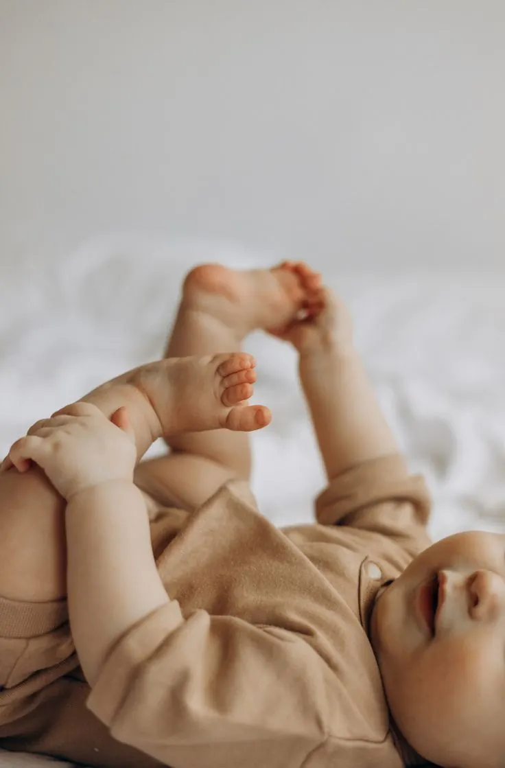 Bebê deitado brincando com os próprios pés