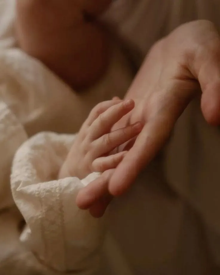 Mão do bebê apoiada na mão da mãe